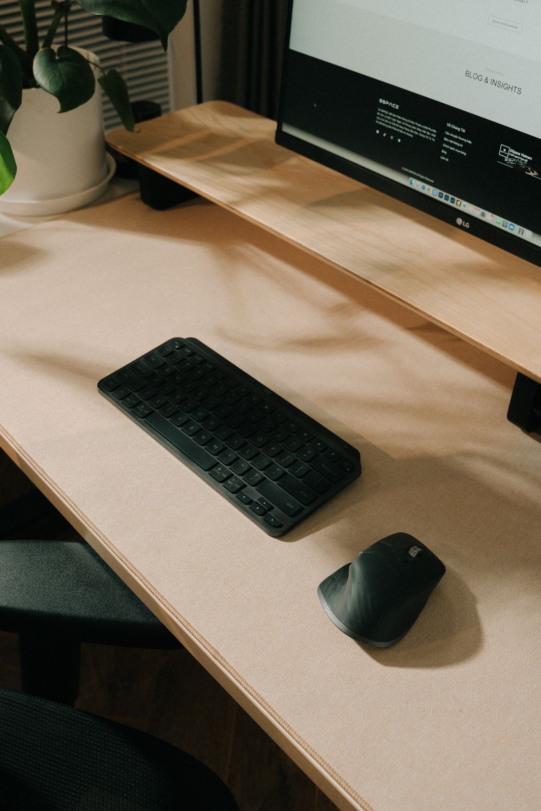 A keyboard, mouse and monitor stand on a neat desk.