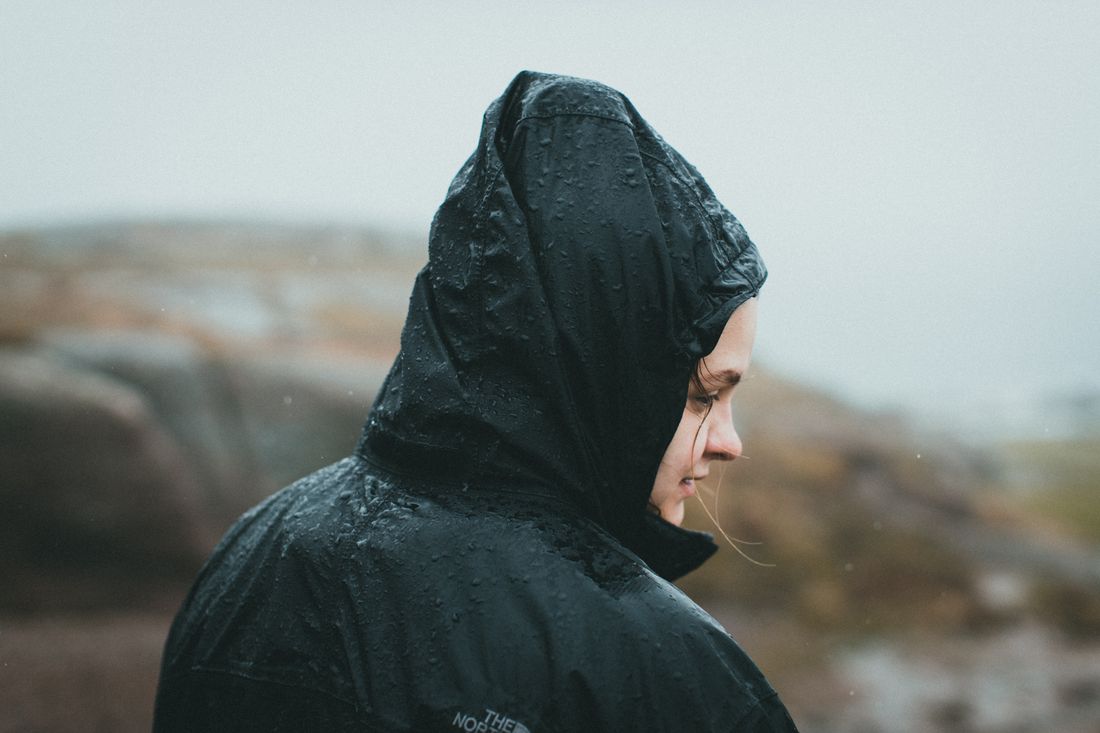 A woman wearing a hooded rain jacket outside.
